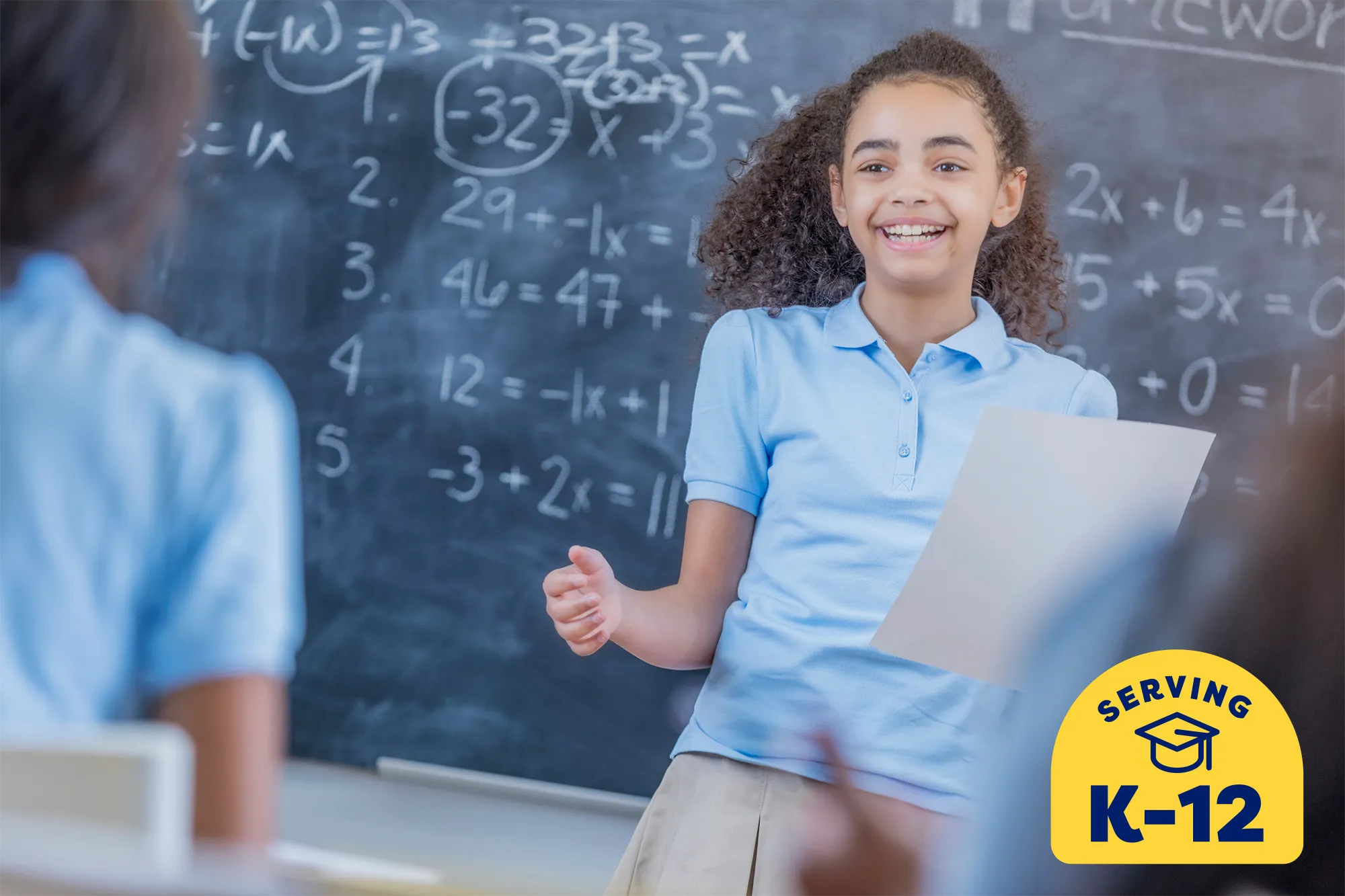 middle school student standing at the chalkboard presenting to her classmates.