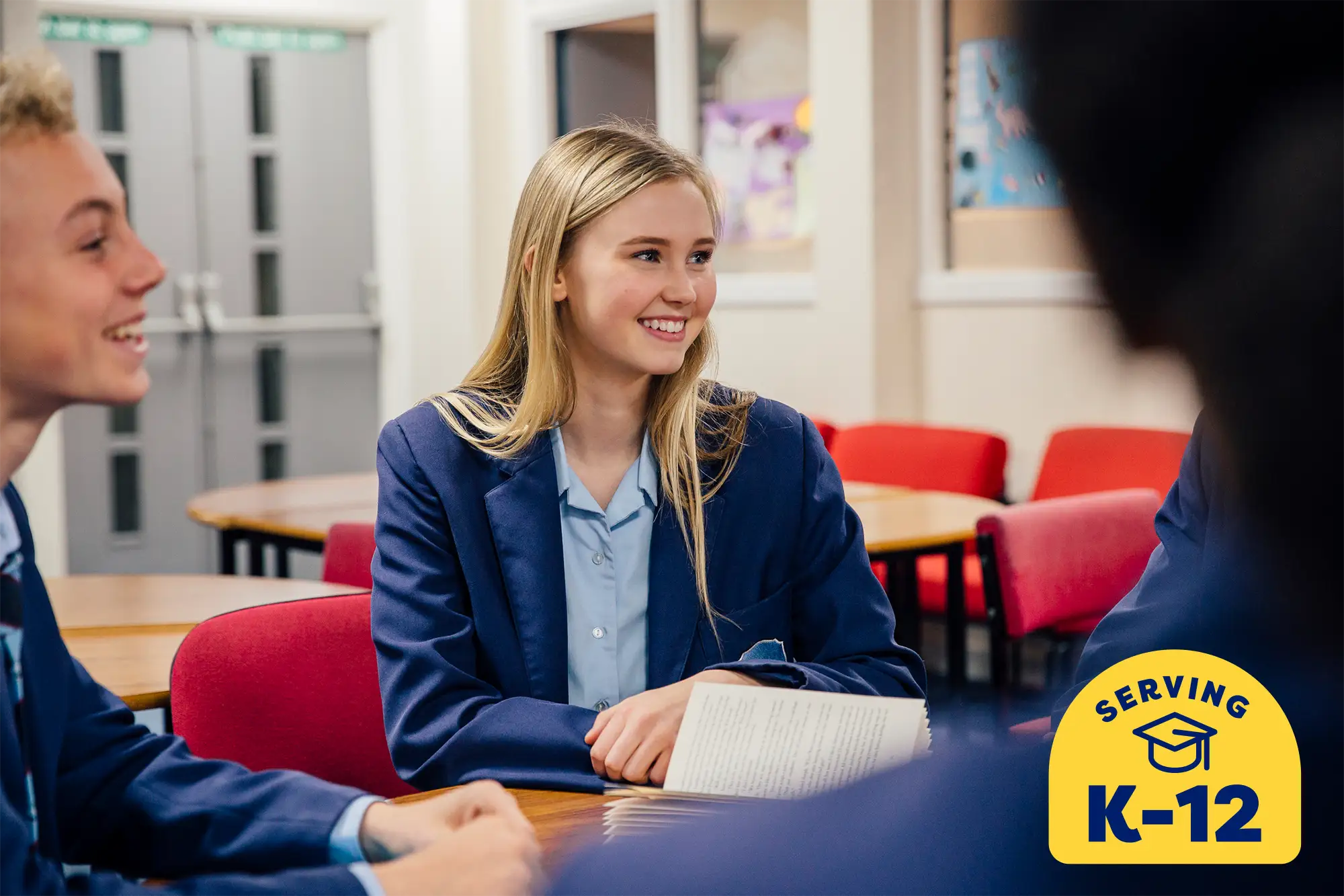 high school student sitting at a table with her peers laughing and smiling