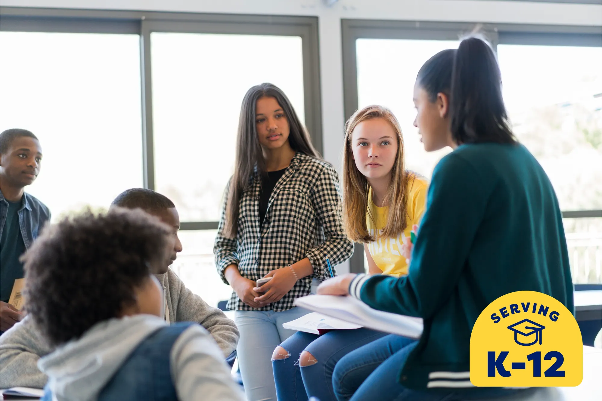 middle school students sitting together in a group in class discussing a class assignment